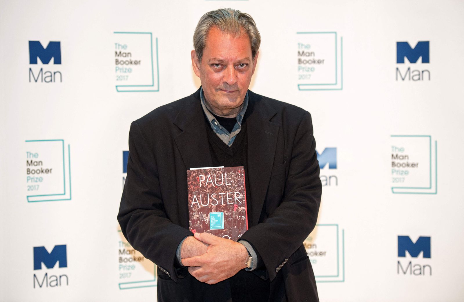 (FILES) US author Paul Auster holds his book '4321' during a photocall at the Royal Festival Hall in London on October 16, 2017, ahead of tomorrow's announcement of the winner of the 2017 Man Booker Prize for Fiction. Paul Auster, the prolific American author whose works included 'The New York Trilogy,' has died of complications from lung cancer, the New York Times reported April 30, 2024. He was 77. Auster died at his home in Brooklyn, the newspaper said, citing a friend of the novelist, Jacki Lyden. (Photo by CHRIS J RATCLIFFE / AFP)