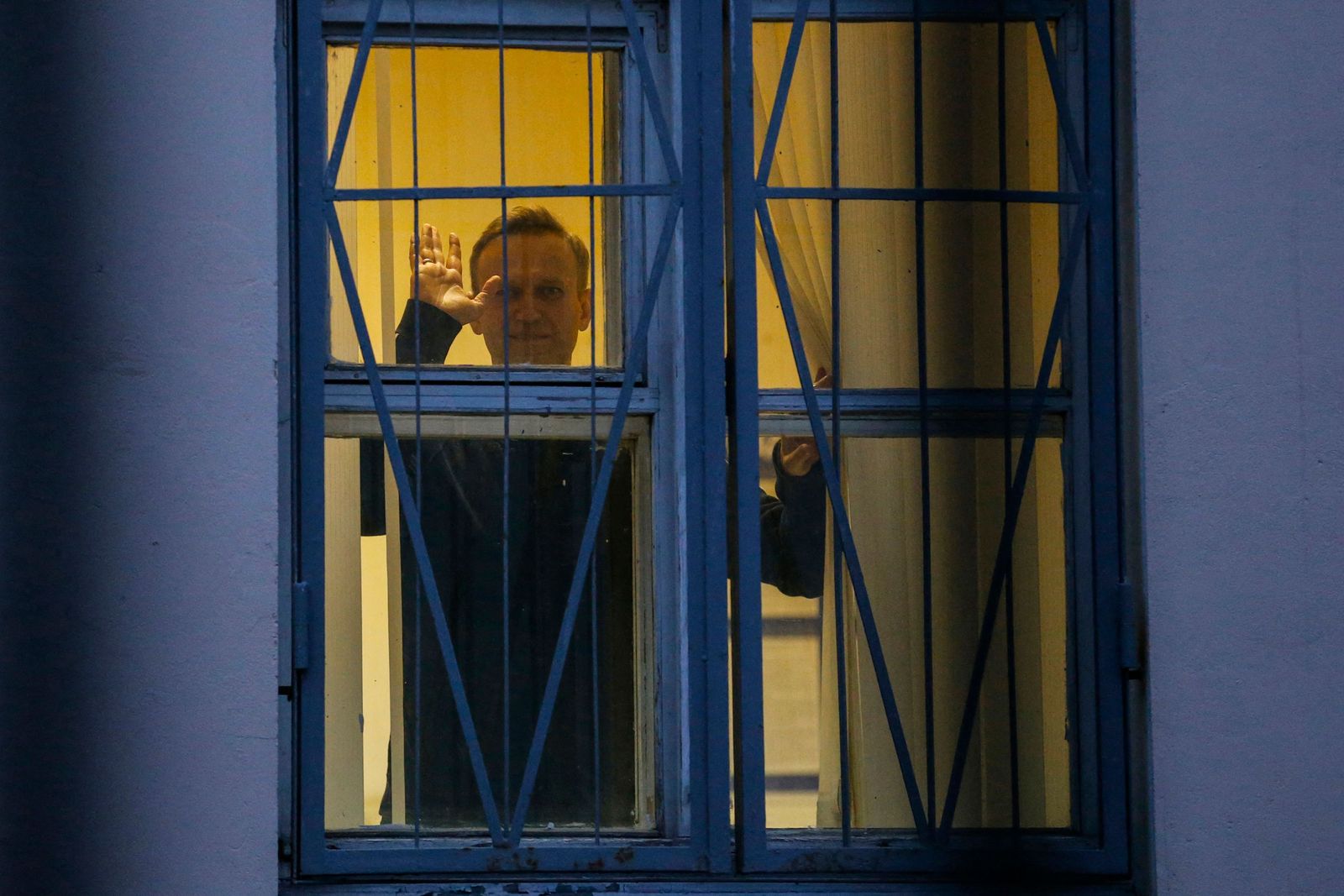 (FILES) Russian opposition leader Alexei Navalny waves from behind the window of a police station in Moscow on September 29, 2017. Russian opposition leader Alexei Navalny died on February 16, 2024 at the Arctic prison colony where he was serving a 19-year-term, Russia's federal penitentiary service said in a statement. (Photo by Maxim ZMEYEV / AFP)