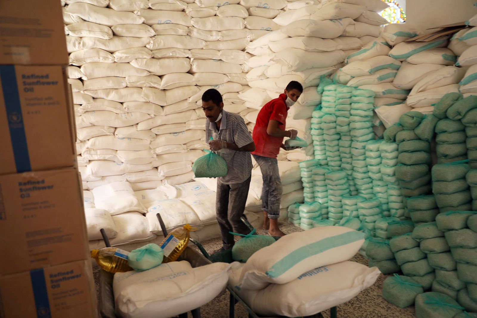 عمال يعدون مواد غذائية للمستفيدين في مركز توزيع أغذية يدعمه برنامج الغذاء العالمي في صنعاء. - REUTERS