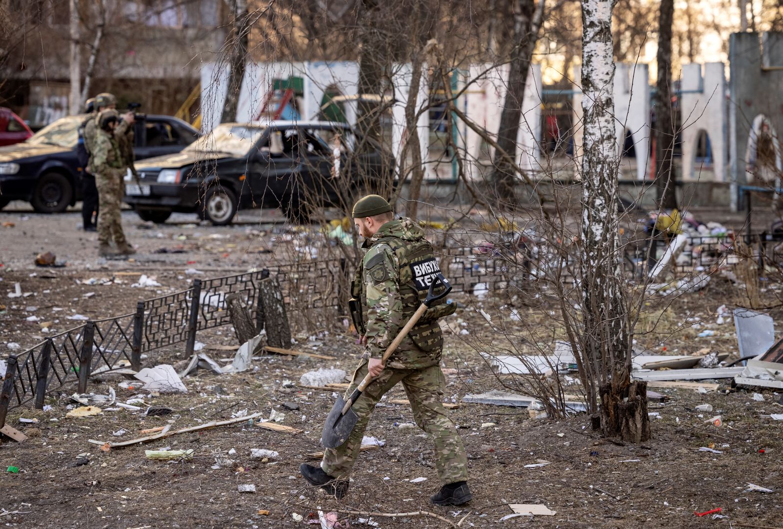 أحد أفراد قوات الدفاع الإقليمية الأوكرانية يسير بالقرب من مبنى سكني أصيب بحطام صاروخ سقط في كييف، 20 مارس 2022 - AFP