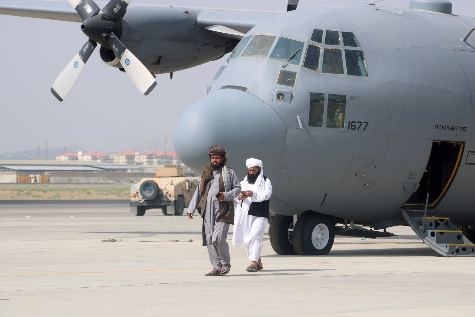 عنصران من قوات طالبان يسيران أمام طائرة عسكرية غداة إتمام انسحاب القوات الأميركية من مطار كابول، 31 أغسطس 2021 - REUTERS