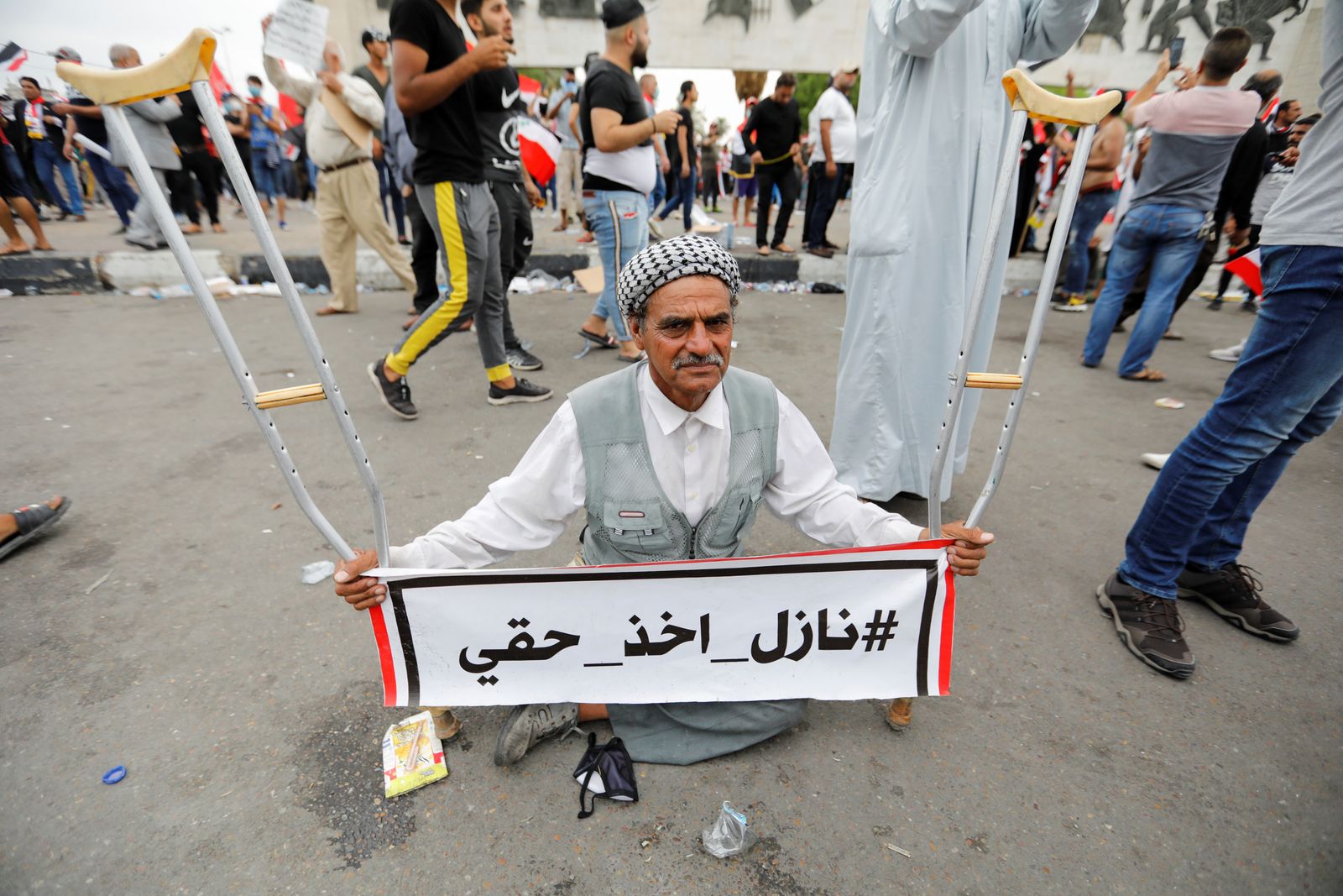 رجل بعكازيه خلال مظاهرة ضد الفساد ونقص الوظائف وسوء الخدمات في بغداد، أكتوبر 2019 - REUTERS