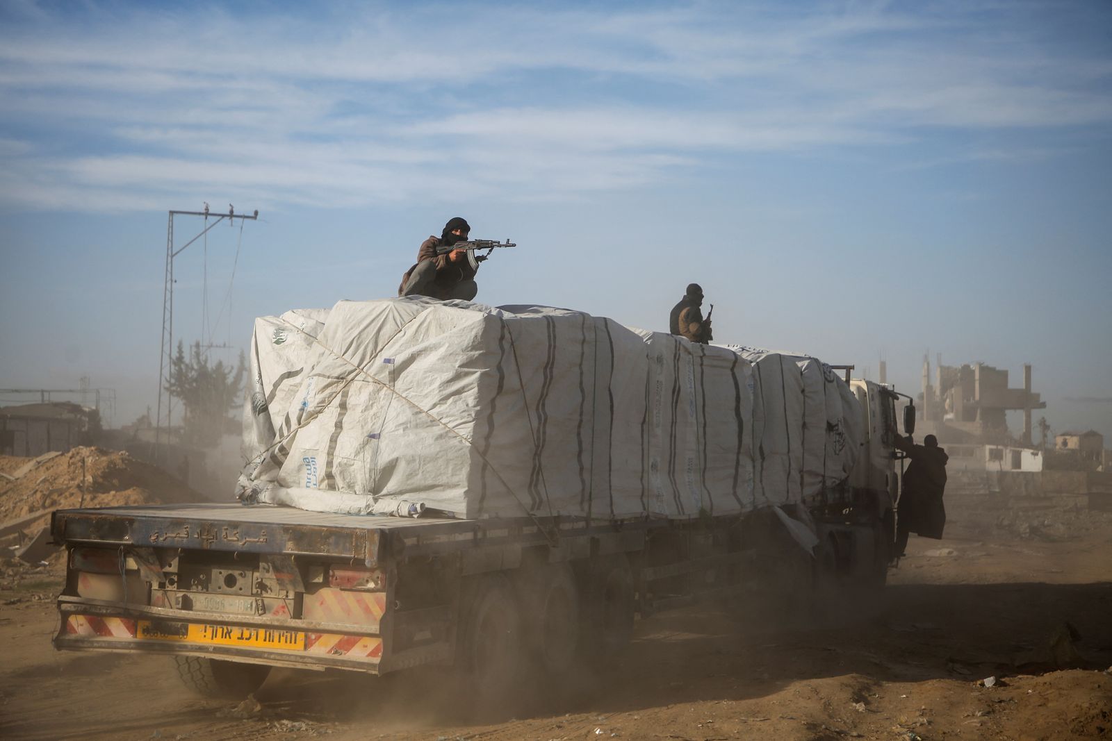 Palestinian gunmen secure aid trucks, following a ceasefire between Israel and Hamas, in Rafah in the southern Gaza Strip, January 20, 2025. REUTERS/Hatem Khaled