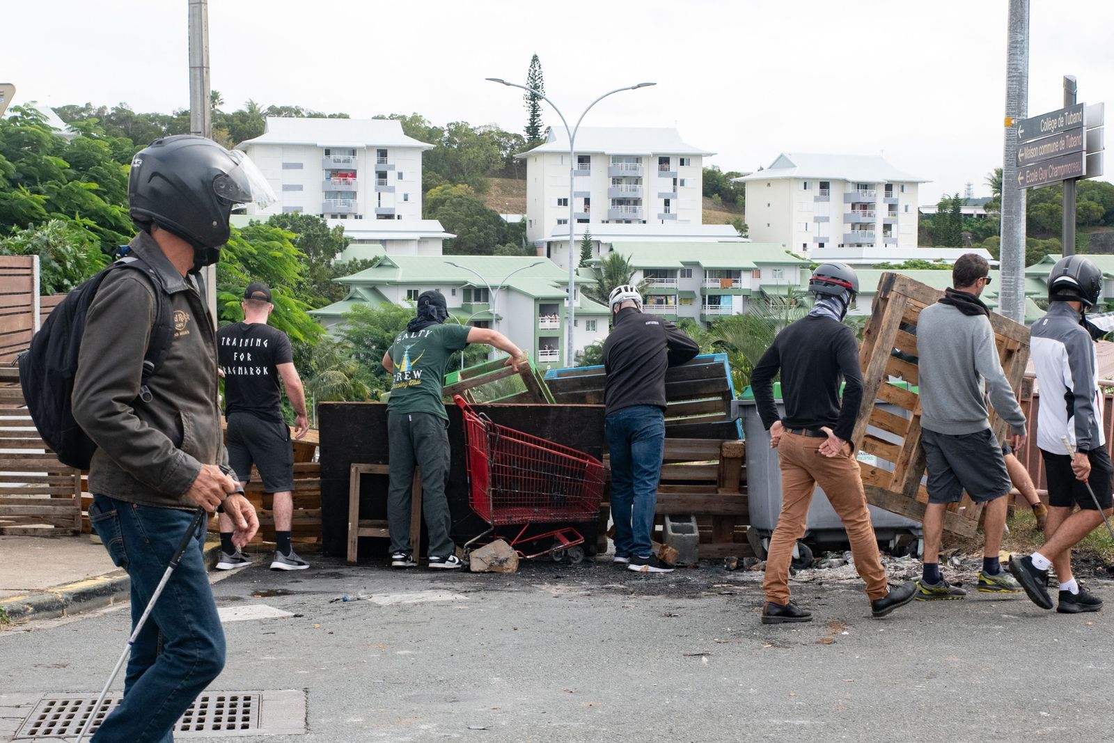 Masked residents watch activists at the entrance to Tuband, in the Motor Pool district of Noumea on May 15, 2024, amid protests linked to a debate on a constitutional bill aimed at enlarging the electorate for upcoming elections of the overseas French territory of New Caledonia. One person was killed, hundreds more were injured, shops were looted and public buildings torched during a second night of rioting in New Caledonia, authorities said Wednesday, as anger over constitutional reforms from Paris boiled over. (Photo by Delphine Mayeur / AFP)