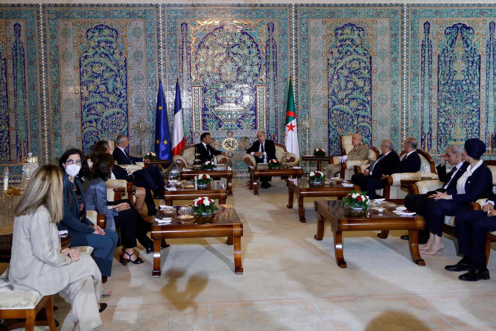 French President Emmanuel Macron (L),  Algeria's President Abdelmadjid Tebboune and their delegations attend a meeting at the VIP lounge of the airport in Algiers on August 25, 2022, at the start of an official visit to Algeria. - The French president starts a three-day visit to Algeria on August 25, to help mend ties with the former French colony, which this year marks its 60th anniversary of independence. (Photo by Ludovic MARIN / AFP) - AFP