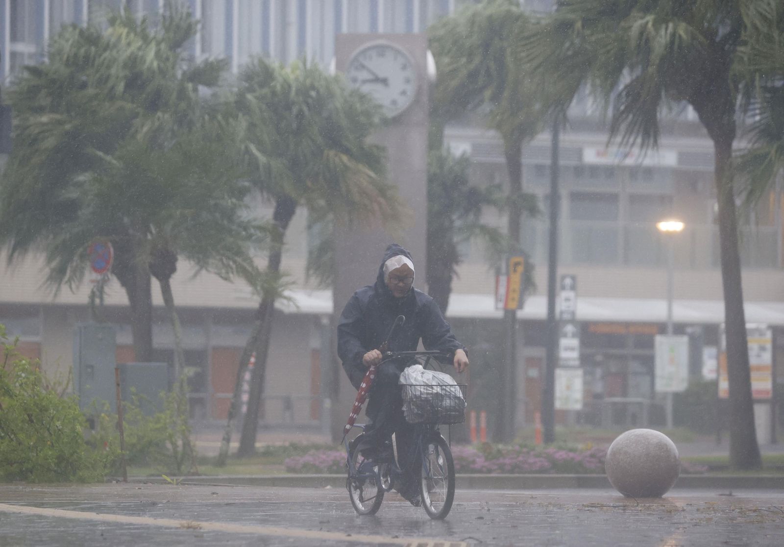 رجل يقود دراجة وسط الأمطار الغزيرة والرياح الناجمة عن إعصار 