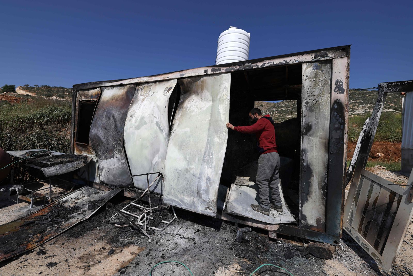 A Palestinian inspects the damage to a structure in the village of Mughayir near Ramallah in the Israeli-occupied West Bank on April 13, 2024, after an attack by Israeli settlers on the village. (Photo by JAAFAR ASHTIYEH / AFP)