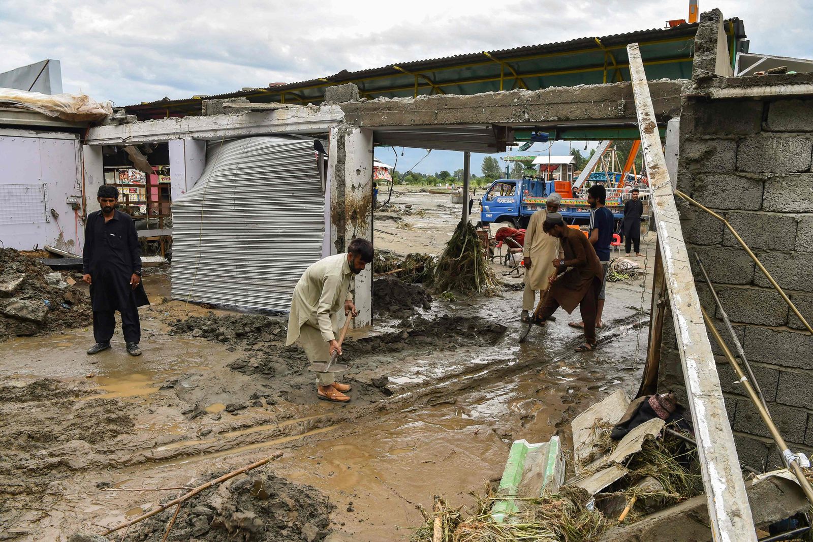 باكستانيون يزيلون الأوحال التي جرفتها السيول قرب متاجرهم في وادي سوات- 27 أغسطس 2022 - AFP