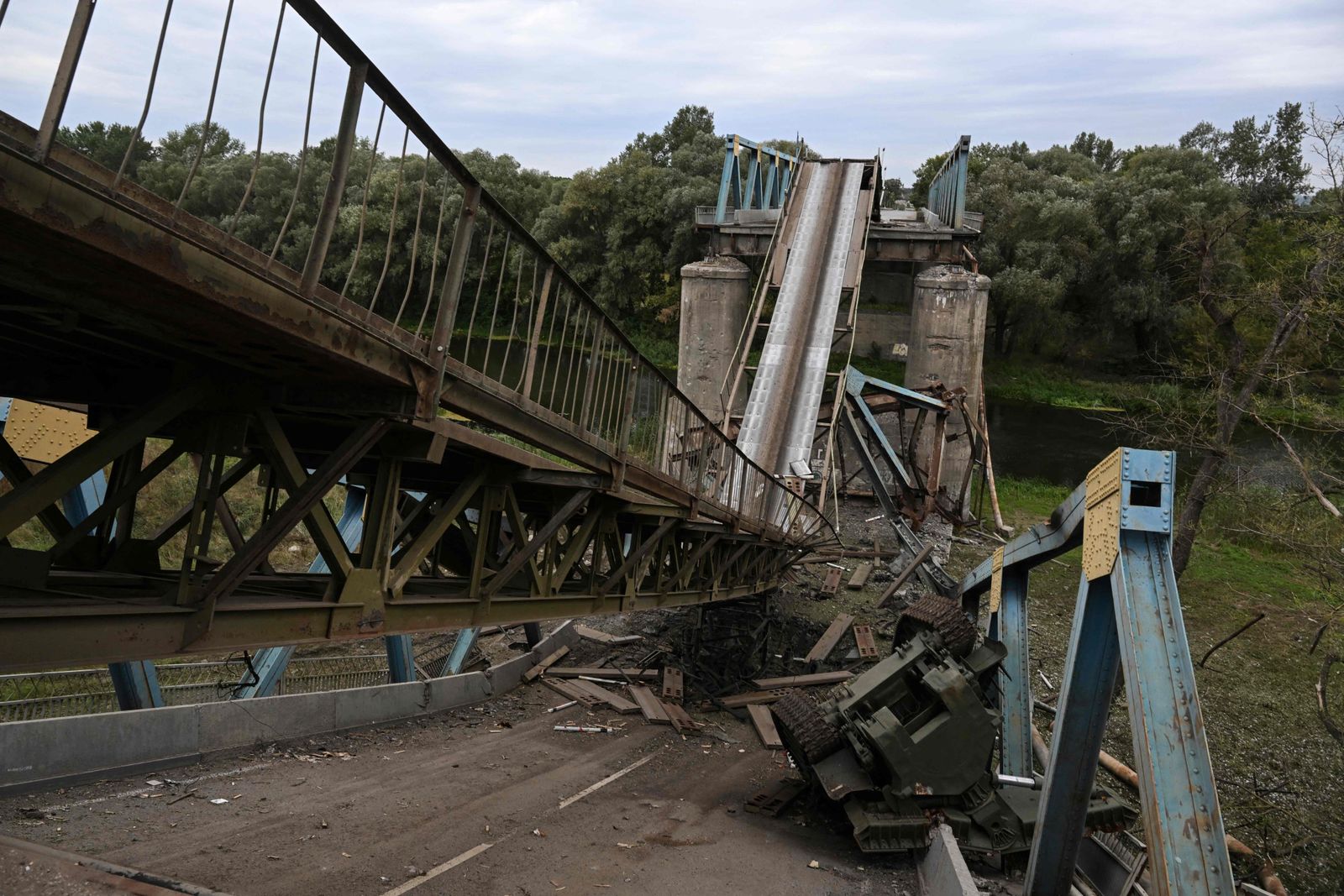 This photograph taken on September 11, 2022 shows a destroyed bridge in the city of Izium, Kramatorsk, eastern Ukraine, amid the Russian invasion of Ukraine. - Ukraine said on Sptember 11, 2022, that its forces were pushing back Russia's military from strategic holdouts in the east of the country after Moscow announced a retreat from Kyiv's sweeping counter-offensive. (Photo by Juan BARRETO / AFP) - AFP