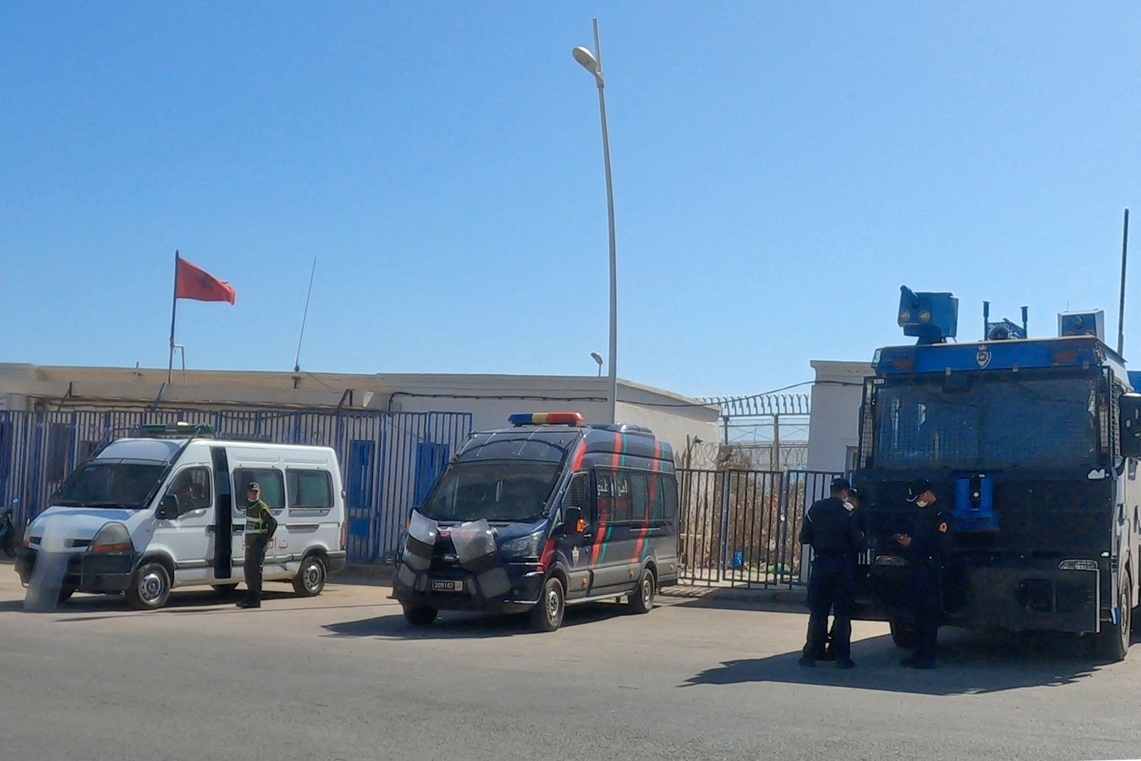 قوات الأمن المغربية تقف أمام السياج الحدودي الفاصل بين المغرب وجيب مليلية الإسباني - 25 يونيو 2022 - AFP