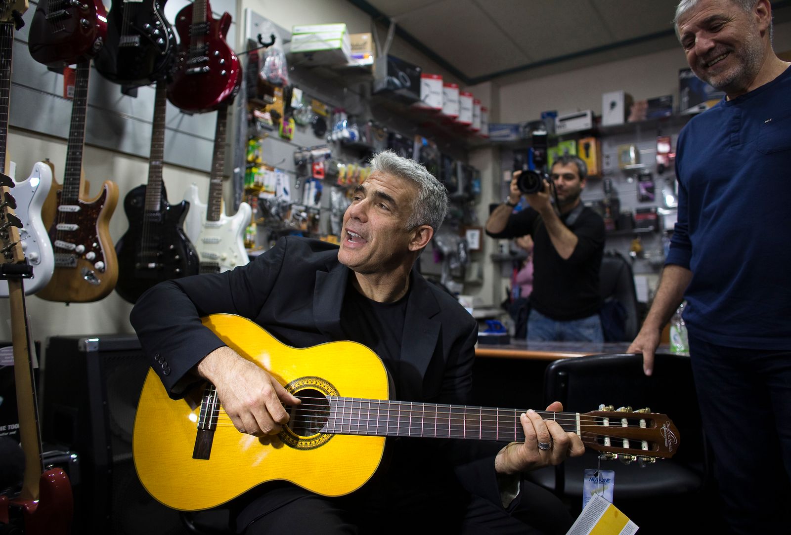 يائير لابيد يعزف على الغيتار في متجر للآلات الموسيقية أثناء حملته الانتخابية في أسدود - 15 مارس 2015 - REUTERS