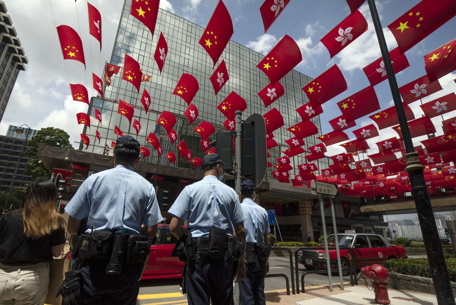 شرطيون تحت أعلام للصين وهونغ كونغ في المدينة - 1 يوليو 2021 - Bloomberg