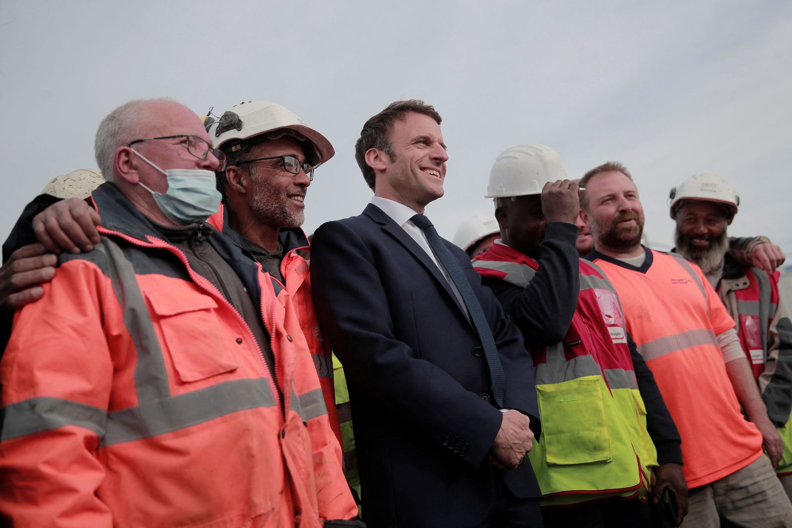 الرئيس الفرنسي إيمانويل ماكرون مع عمال أثناء زيارته موقع بناء في دونان شمال فرنسا - 11 أبريل 2022 - REUTERS