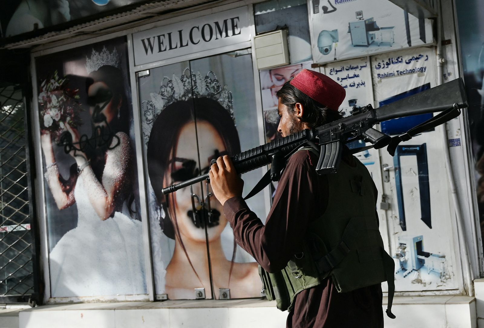 مقاتل من طالبان يمشي أمام صالون تجميل به صور لنساء مشوهة - كابول - 18 أغسطس 2021 - AFP