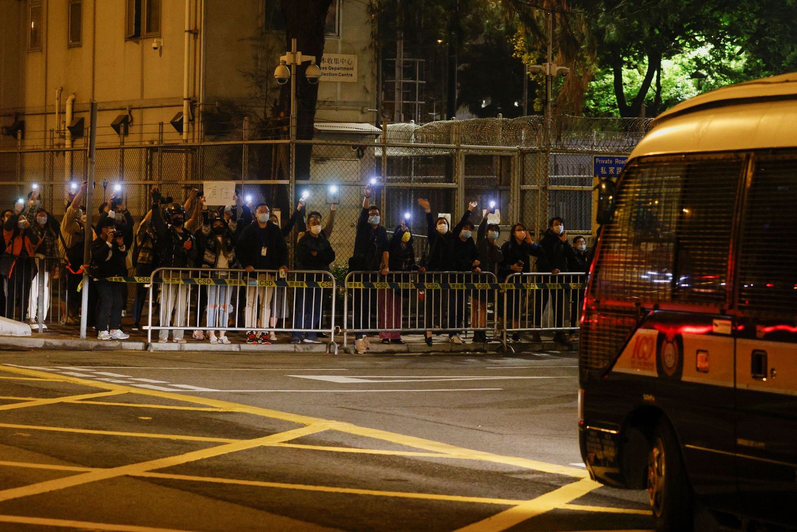 أنصار النشطاء المؤيدين للديمقراطية يحملون مصابيحهم الكهربائية بينما تصل شاحنة السجن إلى المحكمة، في هونغ كونغ. 4 مارس 2021. - REUTERS