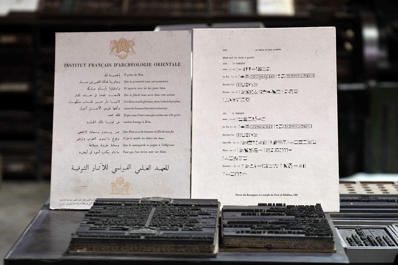 A picture shows text in French, Arabic and Egyptian hieroglyphs behind a machine which allows the printing of ancient Egyptian inscriptions, at the French Institute of Oriental Archaeology in Cairo, on December 10, 2020. - The French-made typecasting machine is over a century old, the Egyptian hieroglyphs 5,000 years. Now, in a Cairo workshop, the mechanical marvel has come to life once again. Out of action for about three decades, a massive Foucher hot metal typecaster built in 1902 has been restored to its former glory. (Photo by Ahmad HASSAN / AFP) - AFP