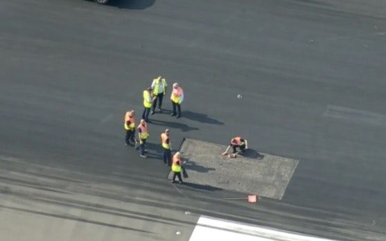 عمال يحاولون إصلاح أجزاء من مهبط الطائرات في مطار 
