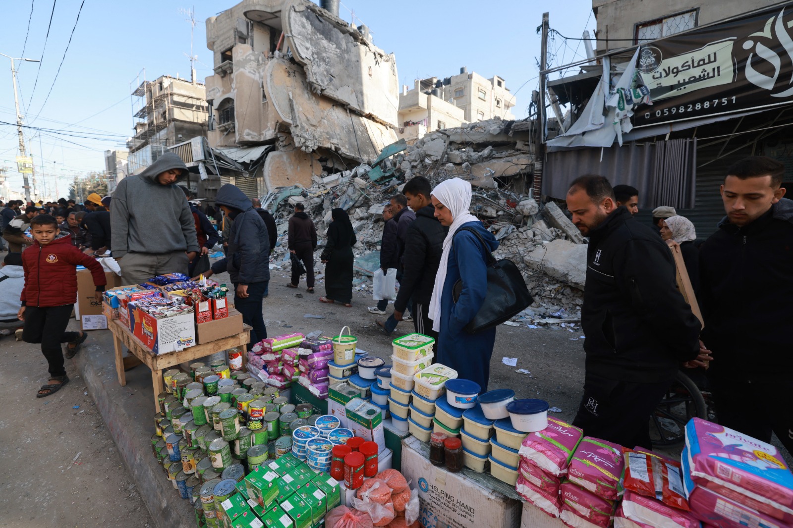 فلسطينيون يسيرون أمام سلع عروضة في شوارع رفح بجنوب قطاع غزة. 10 مارس 2024