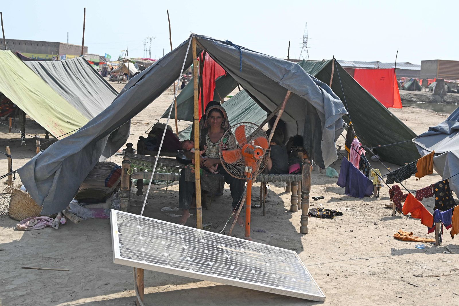 An internally displaced woman sits with her children in a tent at a makeshift camp in Mehar area after heavy monsoon rains in Dadu district, Sindh province on September 7, 2022. - Record monsoon rains have caused devastating floods across Pakistan since June, killing more than 1,200 people and leaving almost a third of the country under water, affecting the lives of 33 million. (Photo by Aamir QURESHI / AFP) - AFP