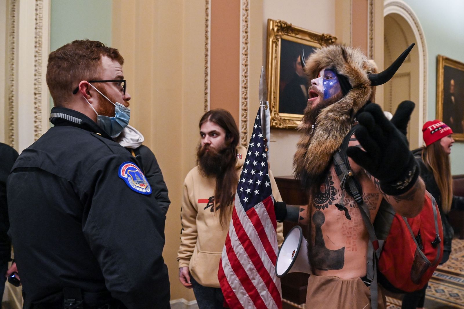 جيكوب تشانسلي يتجادل مع أحد عناصر تأمين الكونغرس خلال اقتحام مبنى الكابيتول الأميركي في 6 يناير 2021 - AFP