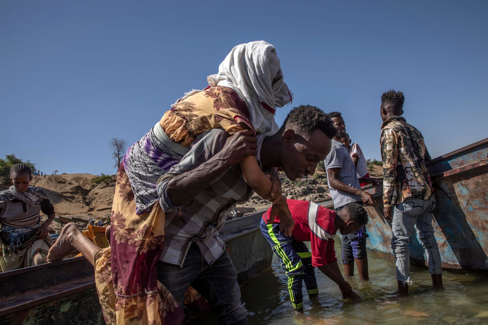 لاجئ فار من تيغراي يحمل عجوزاً لعبور نهر على الحدود السودانية الإثيوبية - 1 ديسمبر 2020 - AP