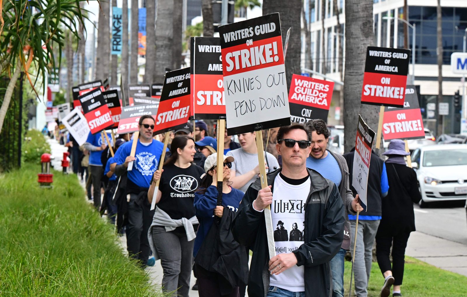 Writer Eric Heisserer hold his sign on the picket line on the fourth day of the strike by the Writers Guild of America in front of Netflix in Hollywood, California, on May 5, 2023. - The Hollywood writers' strike broke out this week over pay, but the refusal of studios like Netflix and Disney to rule out artificial intelligence replacing human scribes in the future has only fueled anger and fear on the picket lines. With their rapidly advancing ability to eerily mimic human conversation, AI programs like ChatGPT have spooked many industries recently. The White House this week summoned Big Tech to discuss the potential risks. (Photo by Frederic J. BROWN / AFP) - AFP