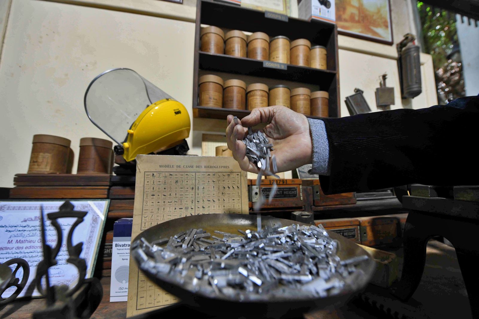 A man prepares parts of a machine which allows the printing of ancient Egyptian inscriptions at the French Institute of Oriental Archaeology in Cairo on December 10, 2020. - The French-made typecasting machine is over a century old, the Egyptian hieroglyphs 5,000 years. Now, in a Cairo workshop, the mechanical marvel has come to life once again. Out of action for about three decades, a massive Foucher hot metal typecaster built in 1902 has been restored to its former glory. (Photo by Ahmad HASSAN / AFP) - AFP