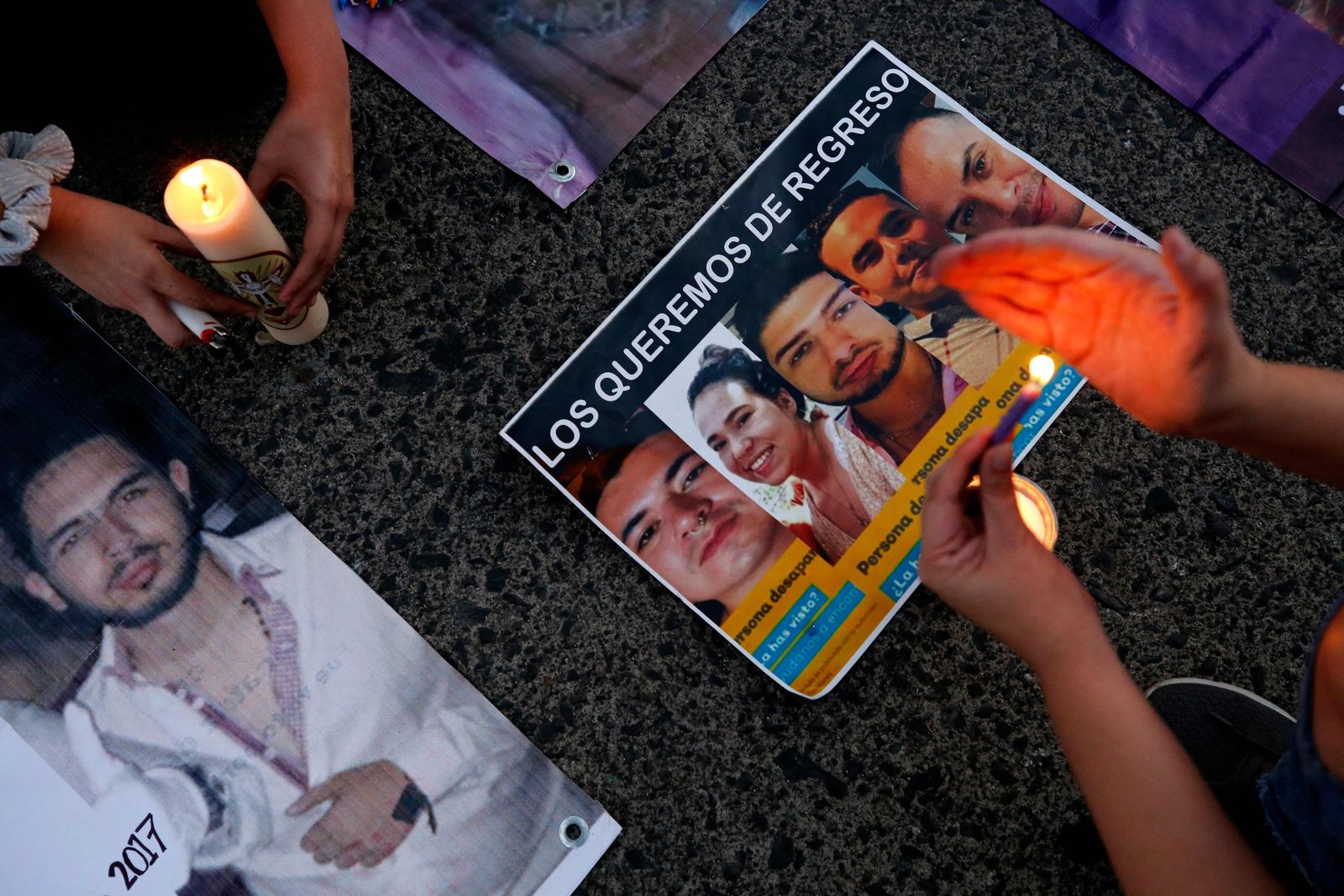 Relatives of eight missing people light candles next to their pictures during a demonstration in Guadalajara, Mexico on June 2, 2023, after human remains were found in a ravine. At least 45 bags with human remains were found in a ravine in the western Mexican state of Jalisco on May 30, 2023, during a search for eight people reported missing last week. The authorities had launched a search for two women and six men, all aged around 30 years, who had been reported missing since around May 20. The missing person reports for each one had been made separately on different days, but investigators found that they all worked at the same call centre. (Photo by ULISES RUIZ / AFP) - AFP