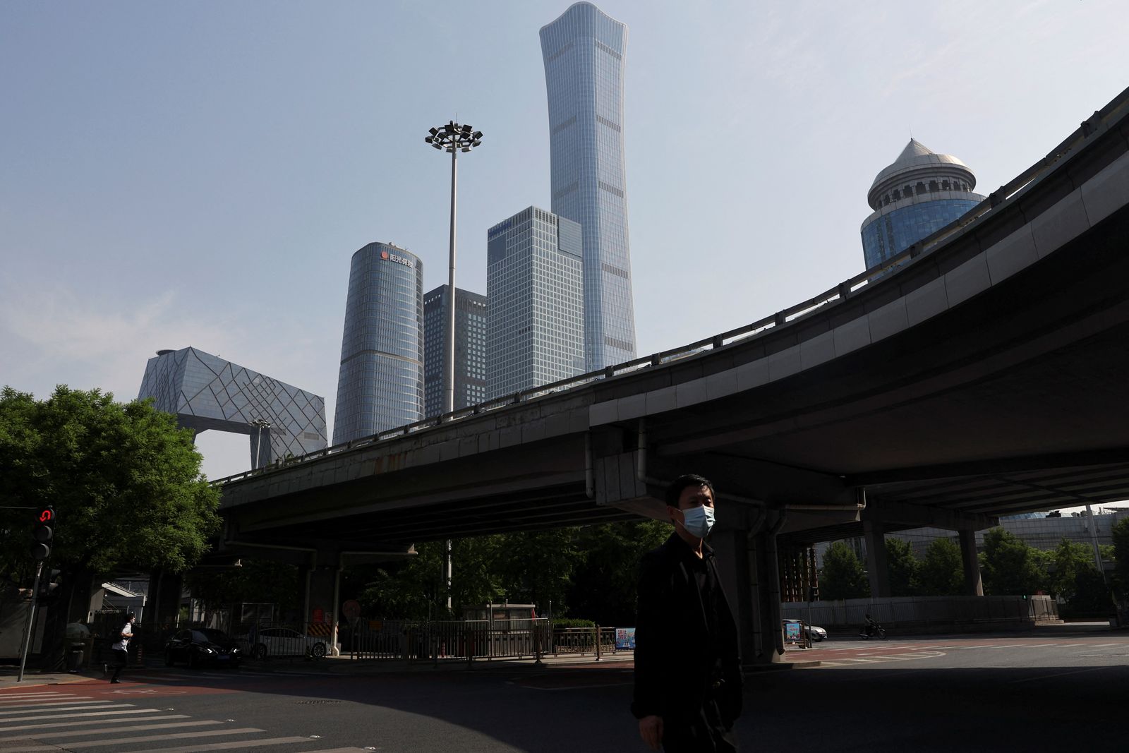 رجل يرتدي الكمامة ويسير في أحد الشوارع الخالية بمنطقة الحي المالي في بكين. 5 مايو 2022 - REUTERS