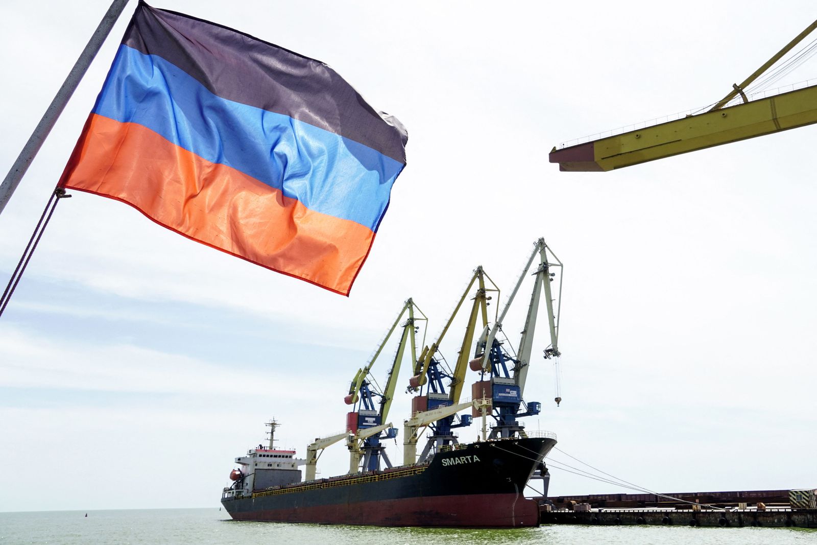 A photograph shows a Donetsk People Republic's flag in front of a ship in the harbour of  Mariupol on June 3, 2022, on the 100th day of the Russian invasion of Ukraine. - Ukrainian President Volodymyr Zelensky vowed victory on the 100th day of Russia's invasion on June 3, 2022, even as Russian troops pounded the eastern Donbas region. (Photo by STRINGER / AFP) - AFP