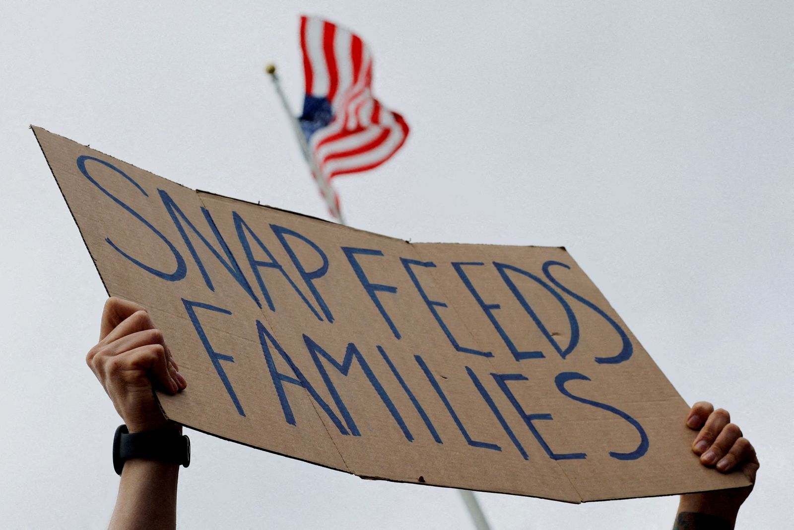 FILE PHOTO: FILE PHOTO: A man holds a sign reading 'SNAP Feeds Families,' as food aid benefits come under threat due to the ongoing U.S. government shutdown, during 'A Rally for SNAP' on the steps of the Massachusetts Statehouse in Boston, Massachusetts, U.S., October 28, 2025. REUTERS/Brian Snyder/File Photo/File Photo