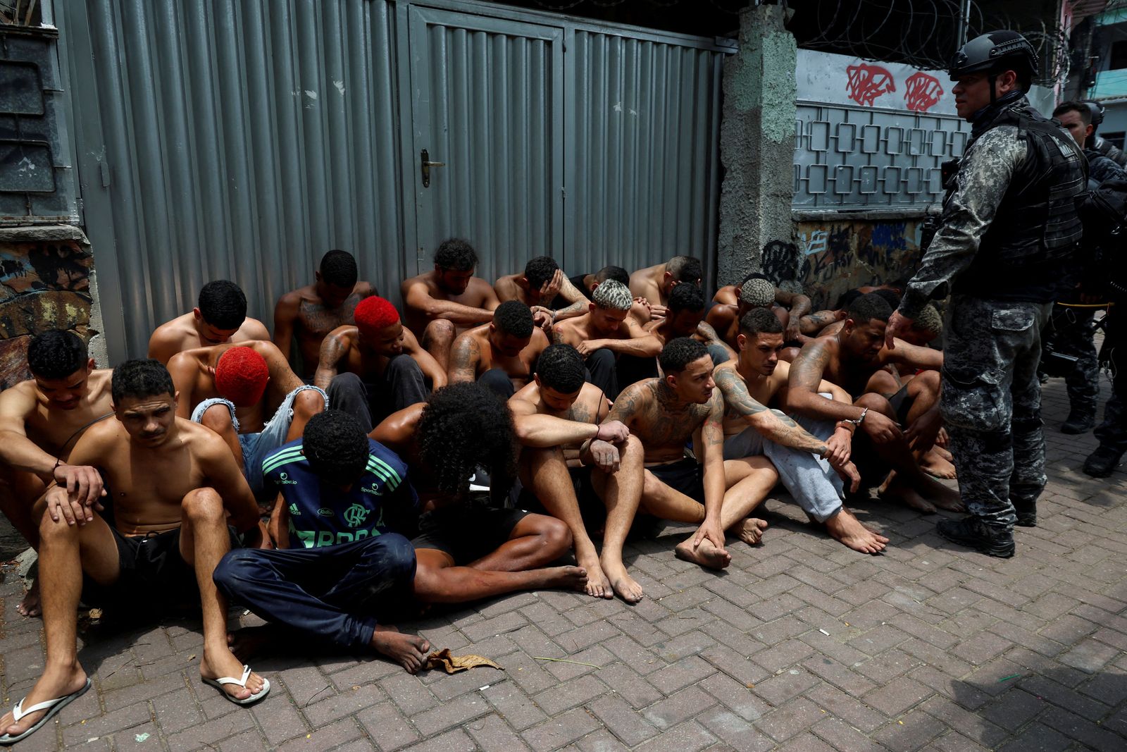 Suspected drug dealers sit on the ground after they were detained by members of the military police special unit, during a police operation against drug trafficking at the favela do Penha, in Rio de Janeiro, Brazil October 28, 2025. REUTERS/Aline Massuca        TPX IMAGES OF THE DAY