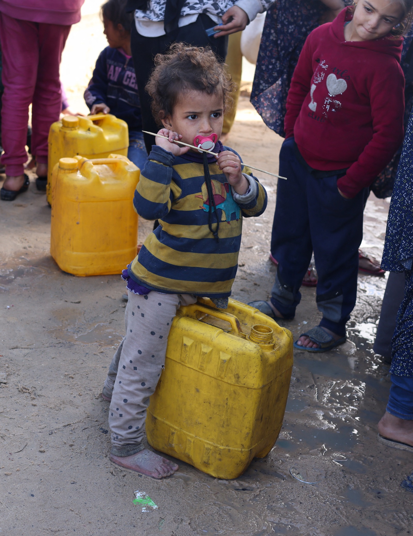 أطفال فلسطينيون ينتظرون الحصول على مياه الشرب ، في مخيم يأوي الأشخاص الذين فروا من منازلهم بسبب الغارات الإسرائيلية، في رفح بجنوب قطاع غزة. 28 يناير 2024