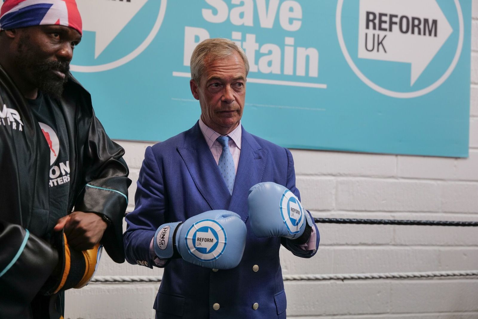 Nigel Farage, leader of Reform UK, wearing boxing gloves, with Derek Chisora, boxer, at a general election campaign event at Seconds Out Boxing gym in Clacton-on-Sea, UK, on Wednesday, July 3, 2024. If Reform UK takes about 15% of the vote or more on Thursday, it could split the right-wing vote in much of the country and significantly ease Labour's path to power. Photographer: Jose Sarmento Matos/Bloomberg