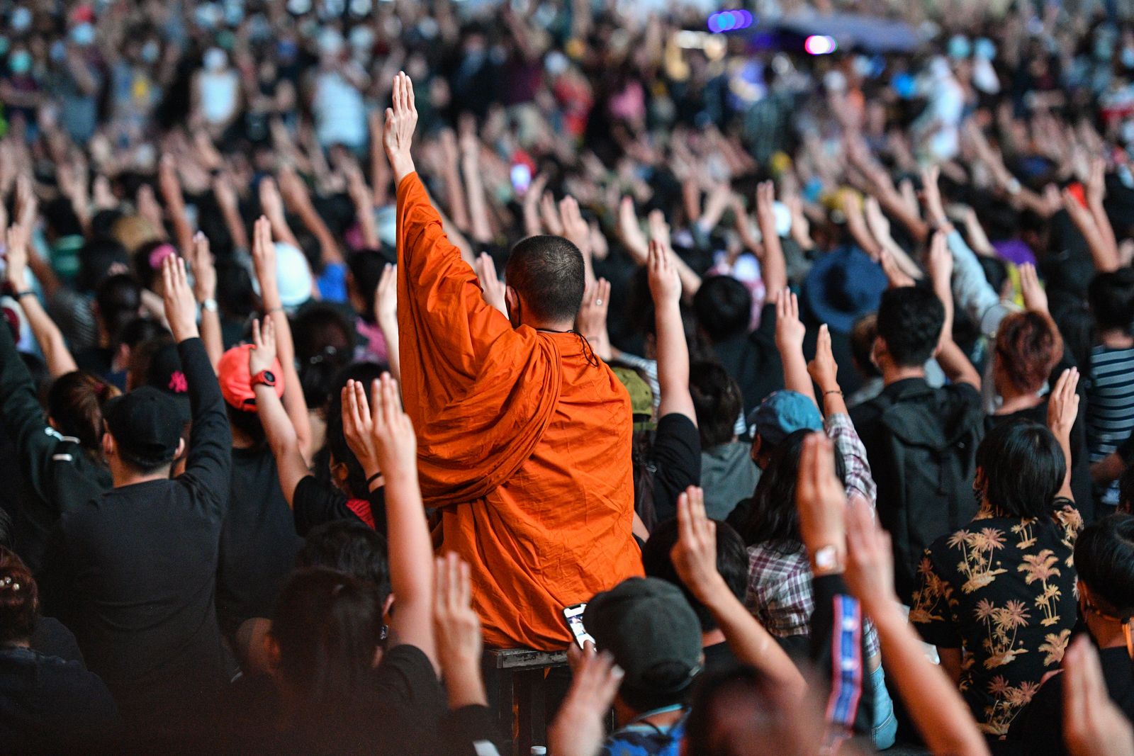 A Buddhist monk gives the three-finger salute with pro-democracy protesters during an anti-government rally at Asok in Bangkok on October 18, 2020, as they continue for the fourth consecutive day to defy an emergency decree banning gatherings. (Photo by Mladen ANTONOV / AFP) - AFP