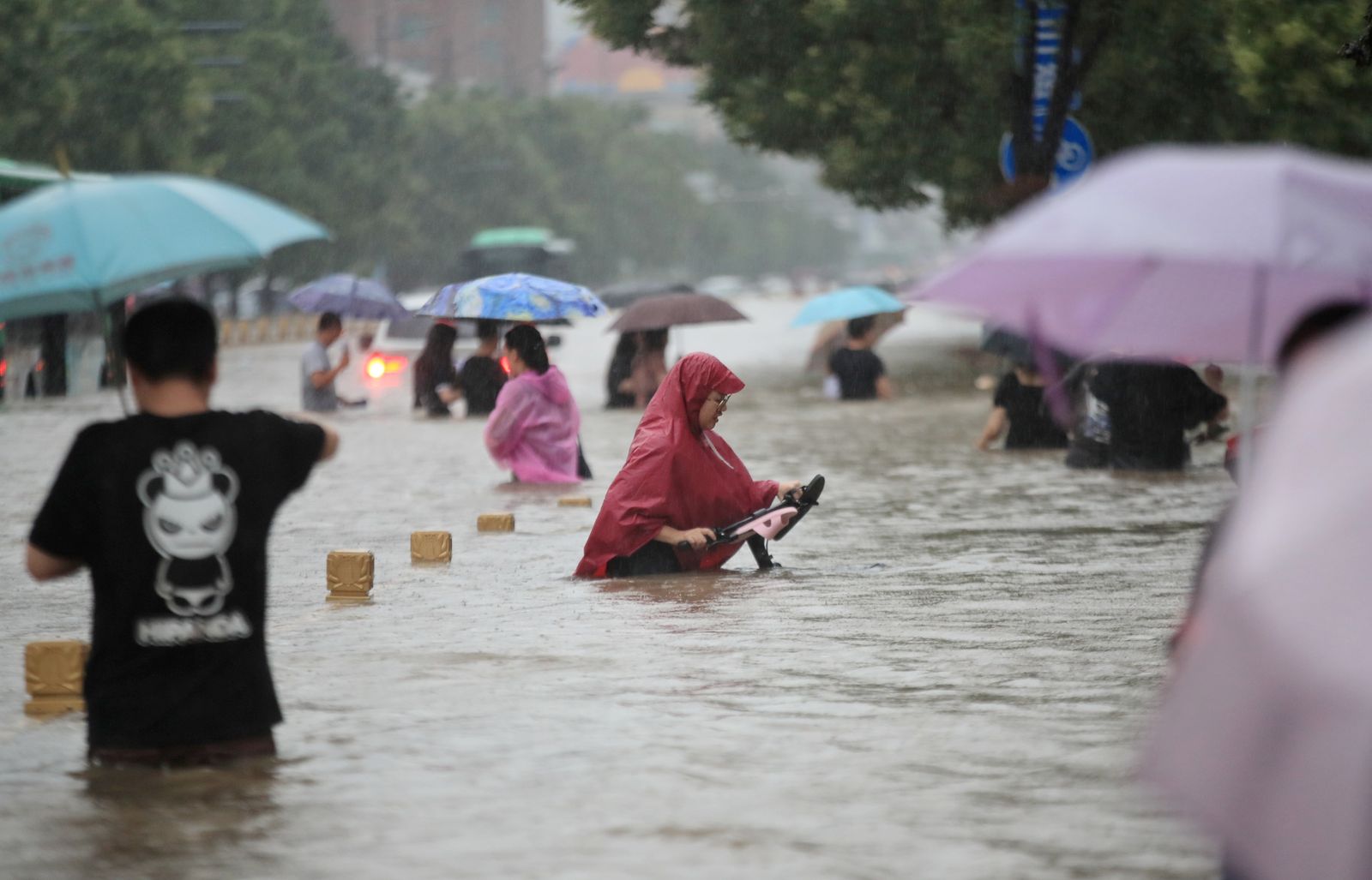 Residents wade through floodwaters on a flooded road amid heavy rainfall in Zhengzhou - VIA REUTERS