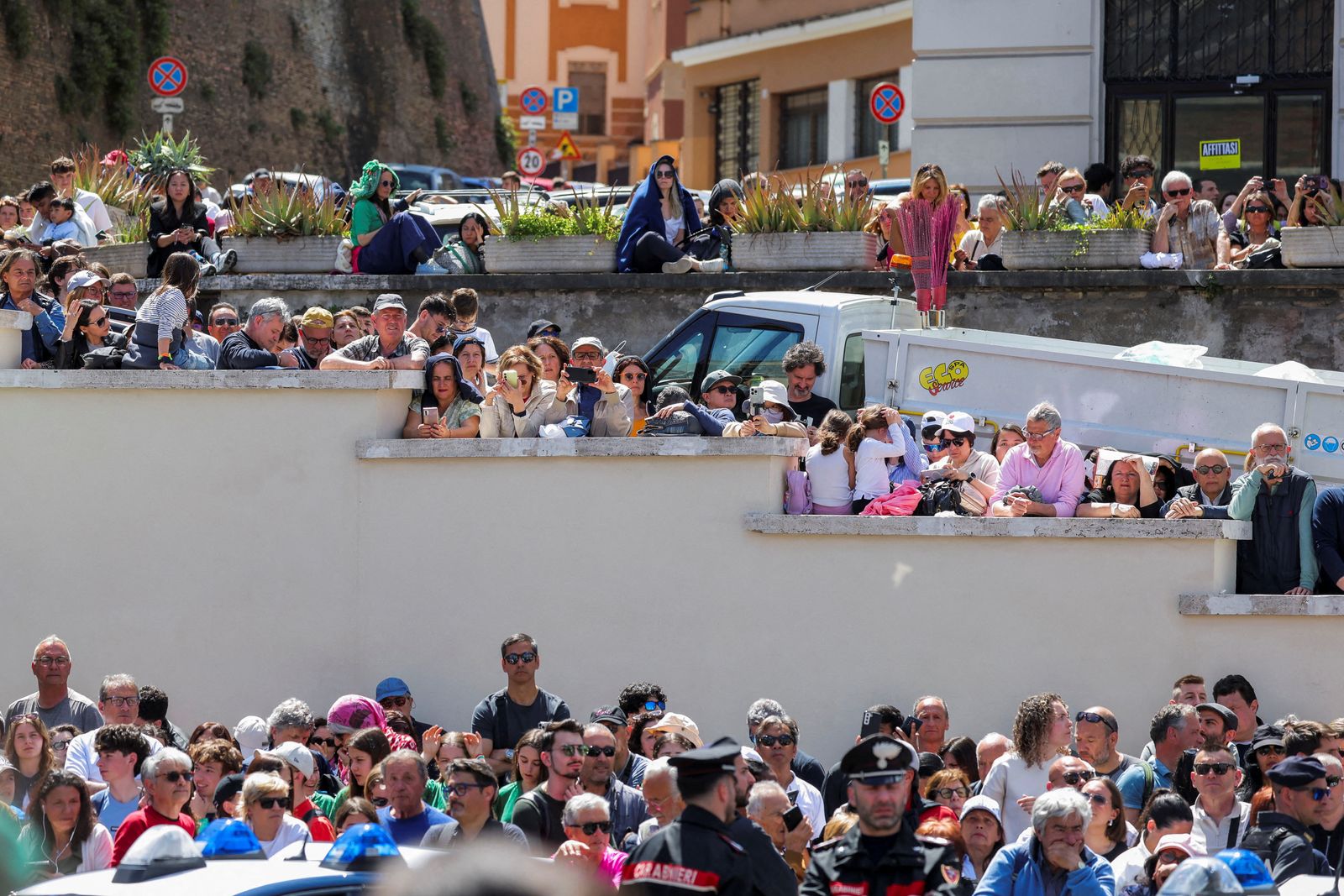 People gather as they wait to see the hearse transferring the coffin of Pope Francis, on the day of the funeral Mass of Pope Francis on St. Peter's Square, in Rome, Italy, April 26, 2025. REUTERS/Kevin Coombs       TPX IMAGES OF THE DAY