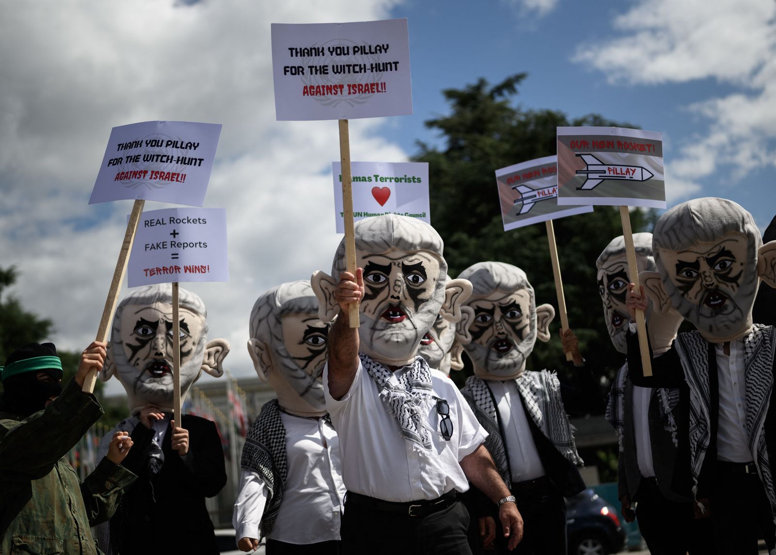 Israel's Defense Force reservists, wearing mask depicting Yahya Sinwar the Hamas chief in the Gaza Strip and holding Palestinian flags, protest outside the United Nations Offices in Geneva on June 7, 2022. - The demonstration, organized by Israeli NOG Shurat HaDin, demands Human Right Council upcoming Pillay Report labeling Israel an �apartheid state� to be cancelled. (Photo by Fabrice COFFRINI / AFP) - AFP