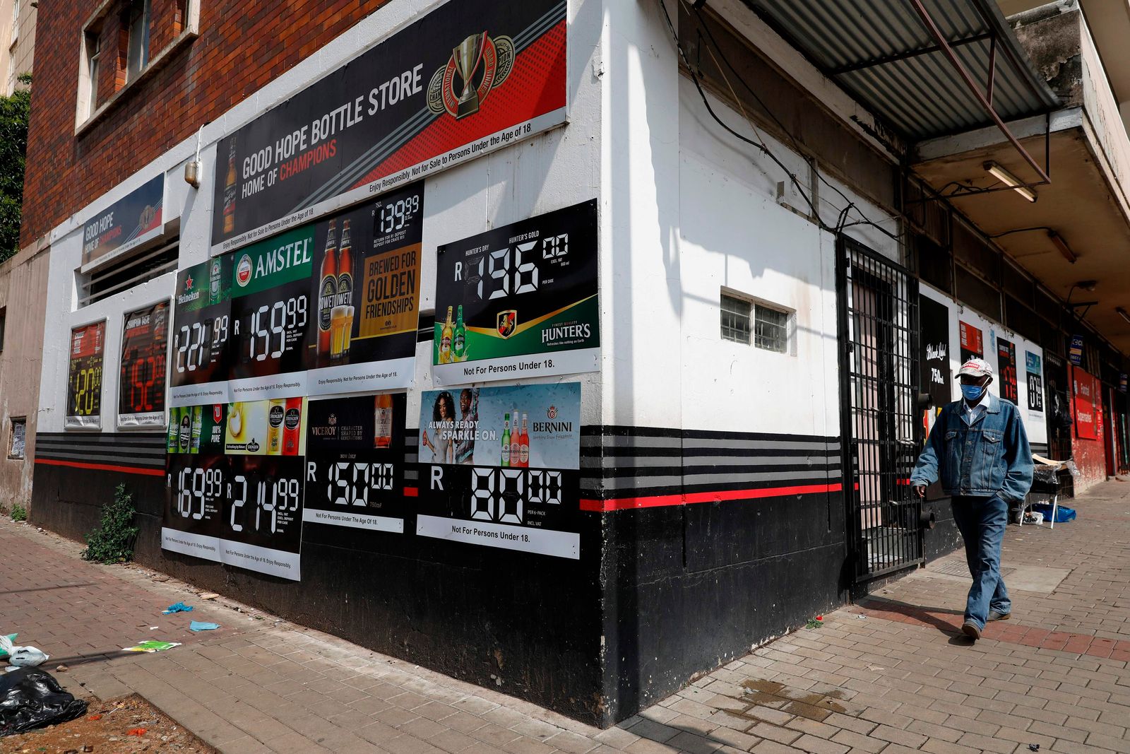 A man walks past a closed liquor store in Hillbrow, Johannesburg, on December 29, 2020. - South African President Cyril Ramaphosa on December 28, 2020 announced a new ban on alcohol sales and said mask-wearing will be mandatory in public after South Africa became the continent's first to record one million coronavirus cases. (Photo by Phill Magakoe / AFP) - AFP
