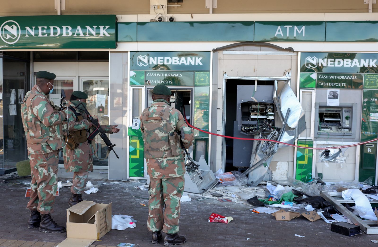 أفراد من الجيش في جنوب إفريقيا أمام أجهزة صراف آلي تالفة خارج أحد البنوك، بينما تشهد البلاد اضطرابات مرتبطة بسجن الرئيس السابق جاكوب زوما، في سويتو، جنوب إفريقيا. 13 يوليو 2021 - REUTERS