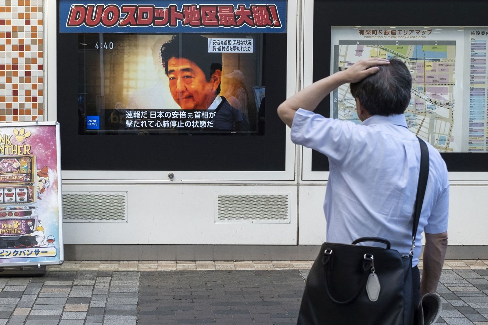 رجل ينظر إلى بث تلفزيوني يعرض أخبارًا عن الهجوم على رئيس الوزراء الياباني السابق شينزو آبي في أحد شوارع طوكيو - 8 يوليو 2022 - AFP