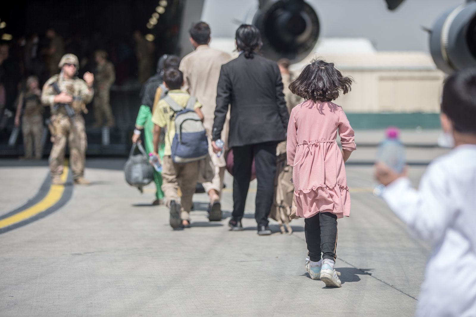 عائلات تتوجه إلى طائرة نقل تابعة للقوات الجوية الأميركية أثناء عمليات الإجلاء في مطار كابول- 23 أغسطس 2021 - via REUTERS