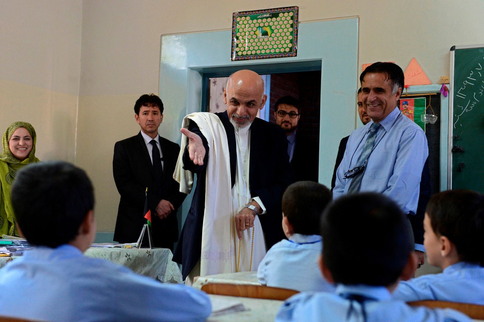 الرئيس الأفغاني السابق أشرف غني (وسط) خلال زيارته مدرسة في كابول - 30 سبتمبر 2014 - REUTERS