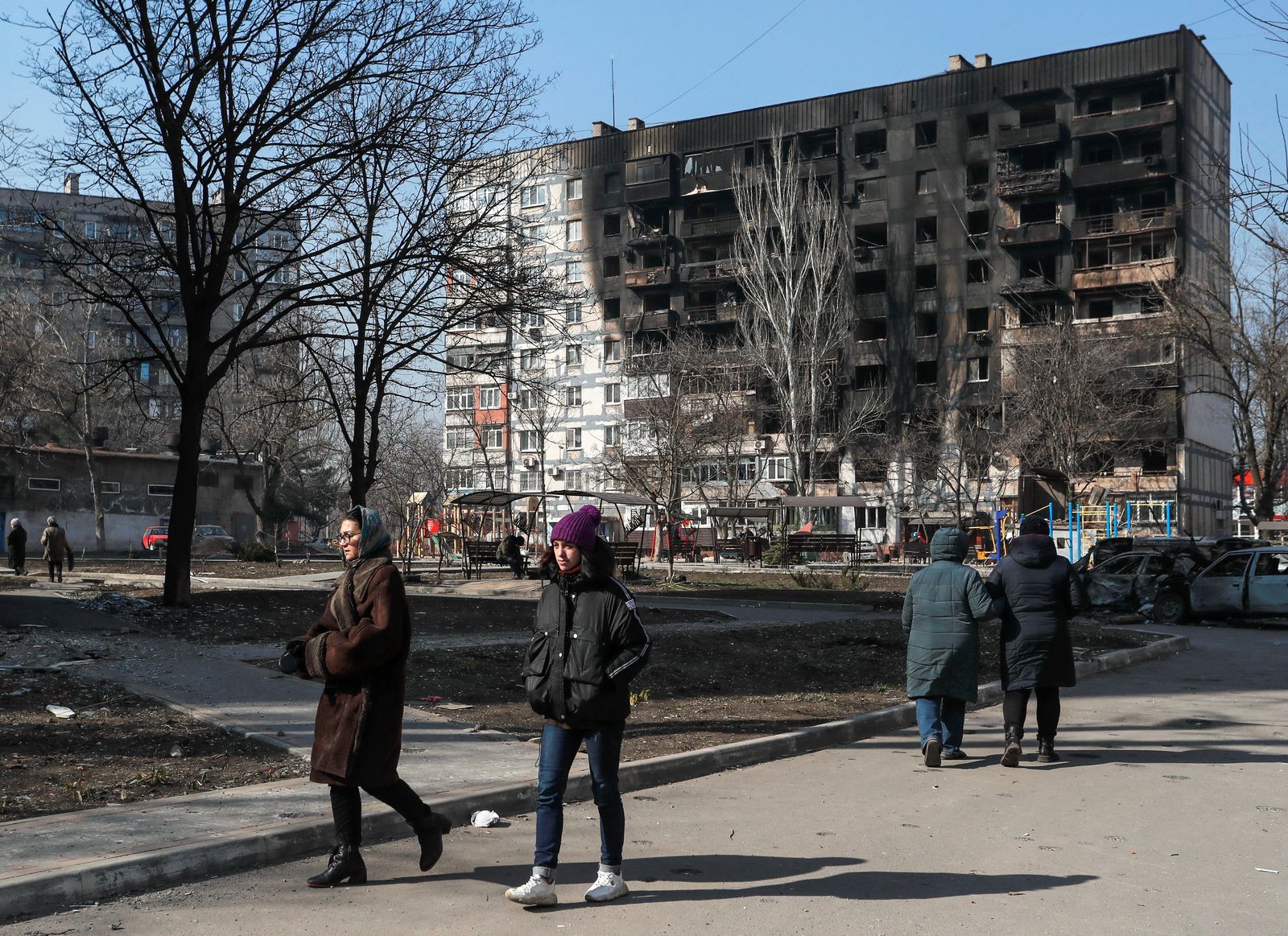 عدد من الأوكرانيين بالقرب من مبنى محترق بسبب القصف الروسي في مدينة ماريوبل جنوب البلاد - 23 مارس 2022 - REUTERS