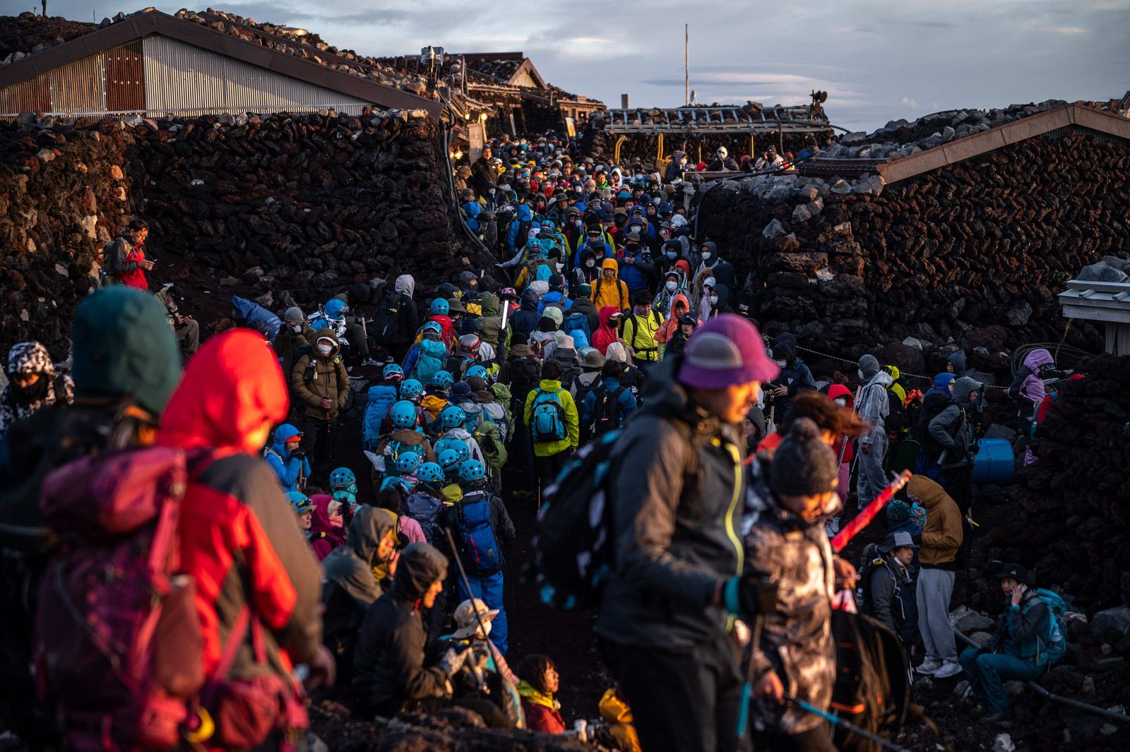 (FILES) People gather after watching the sunrise from the summit of Mount Fuji early on August 15, 2022, some 70 kilometres (43 miles) west of the capital Tokyo. A surge in demand for rest cabins on Mount Fuji has led Japanese officials to call for crowd control measures including potential entry restrictions during the summer 2023 climbing season. (Photo by Philip FONG / AFP)