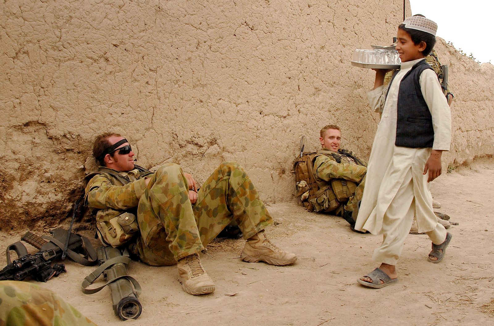 طفل أفغاني يمر أمام جنود ضمن القوات الأجنبية في أفغانستان عام 2008 - AFP