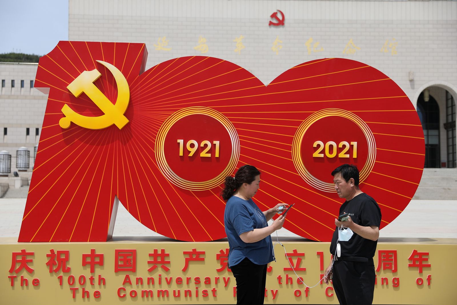 يقفان أمام شعار لمناسبة الذكرى المئوية لتأسيس الحزب الشيوعي الصيني، في يانان بمقاطعة شنشي - 10 مايو 2021 - REUTERS