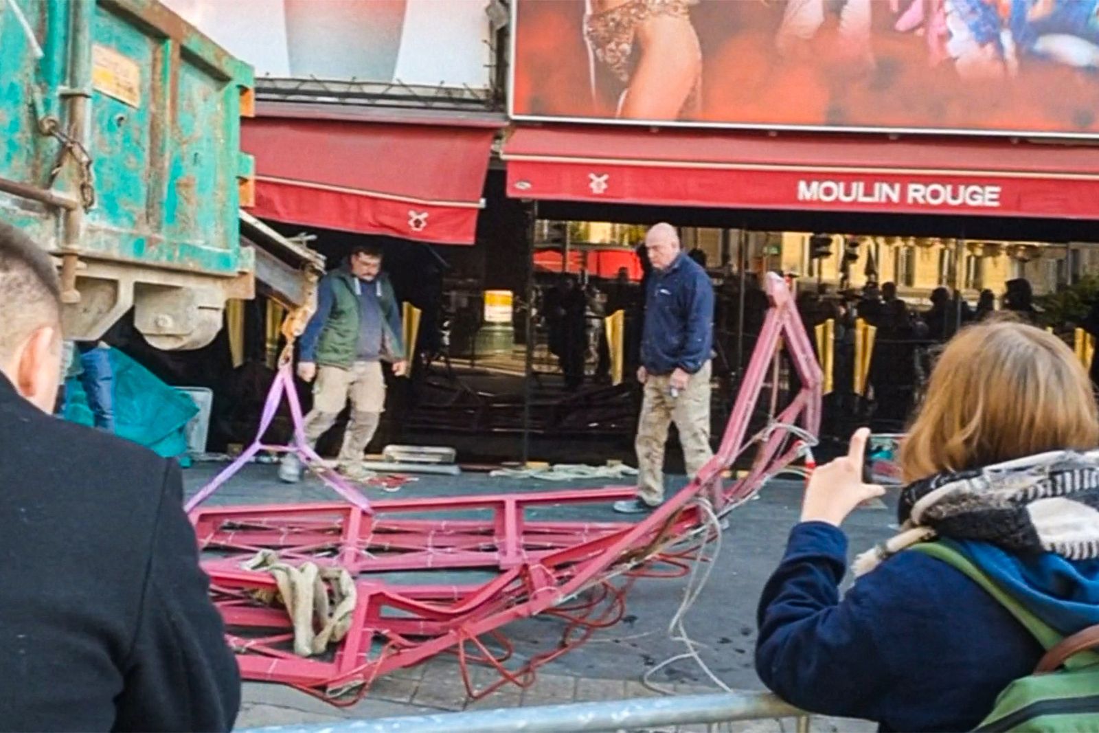 A framegrab taken from an AFP video shot in Paris on April 25, 2024, shows one of the blades of the Moulin Rouge musical cabaret on the pavement after it collapsed overnight, prior to be removed by workers. The blades of the windmill on top of the Moulin Rouge cabaret, one of the most famous landmarks in Paris, collapsed during the night of April 24, 2025, firefighters said, just months before the French capital hosts the Olympics. (Photo by Marine DO-VALE / AFP)