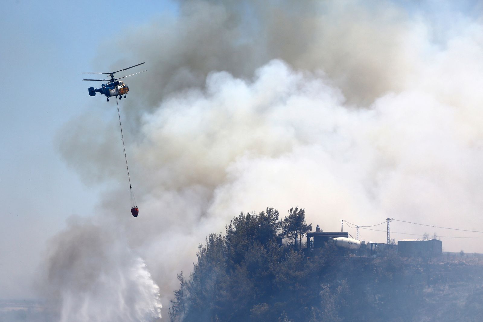A firefighting helicopter drops water to extinguish a wildfire in the Aksu district of Antalya, a Mediterranean city in southern Turkey, July 25, 2025. REUTERS/Kaan Soyturk