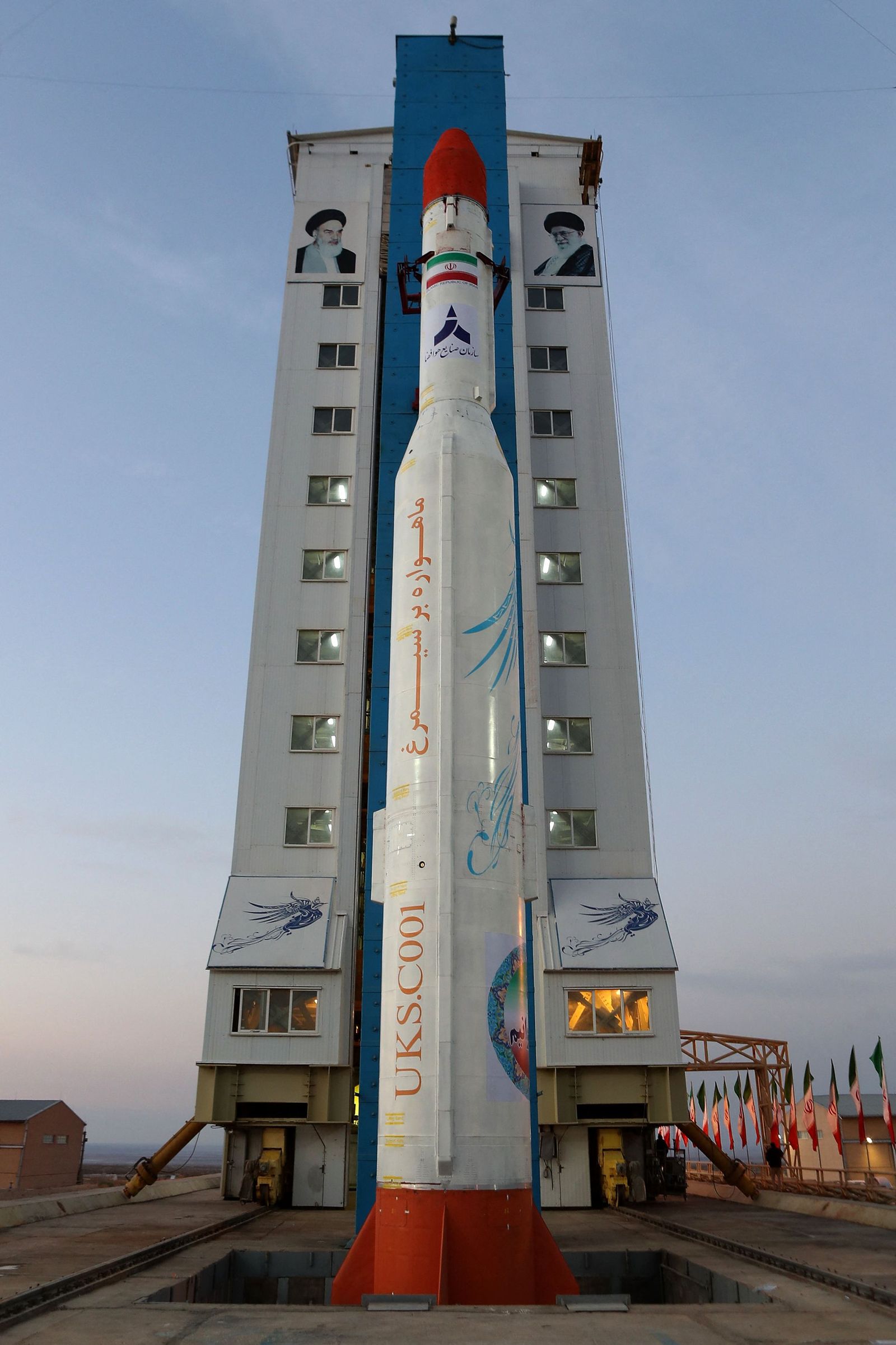 A handout picture released by Iran's Defence Ministry on December 30, 2021 shows a Simorgh (Phoenix) satellite rocket on a launch pad beneath the portraits of Iran's Supreme leader Ayatollah Ali Khamenei (R) and the late founder of the Islamic republic Ayatollah Ruhollah Khomeini (L) ahead at an undisclosed location in Iran. - The Islamic republic announced today it had carried out a new space launch, in a move likely to irk Western powers amid tough talks on reviving a 2015 nuclear deal. (Photo by IRANIAN DEFENCE MINISTRY / AFP) / ==  RESTRICTED TO EDITORIAL USE - MANDATORY CREDIT 